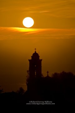 Silhouette of Greek chapel against setting sun
