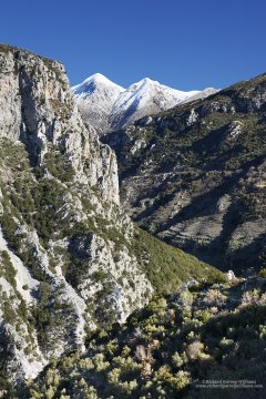 Dramatic landscape photograph showing snow-capped mountains and deep gorge in Greece