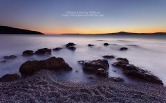 Long exposure photograph of a tranquil coastal scene across the Messinian bay